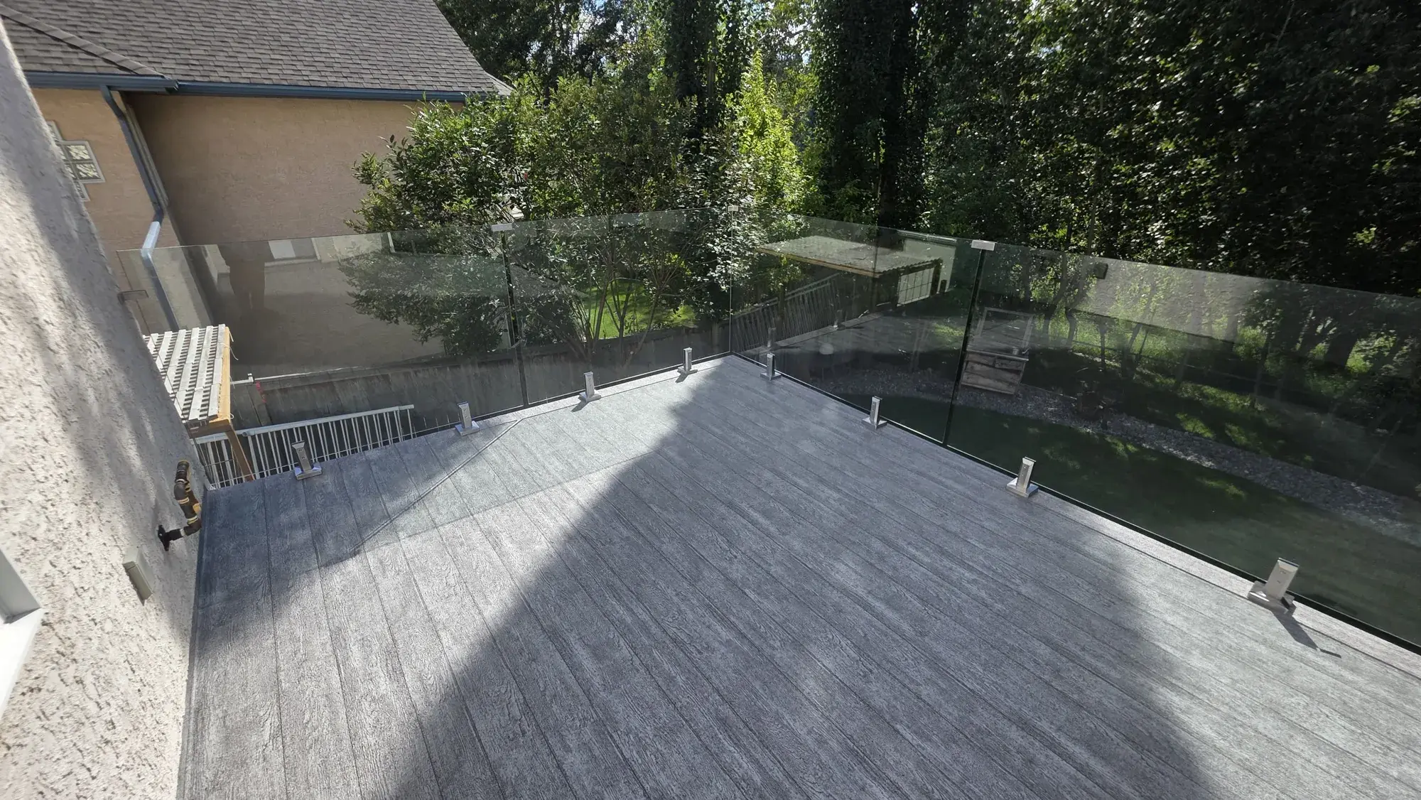 A second-storey vinyl deck with glass railing above a finished lower level
